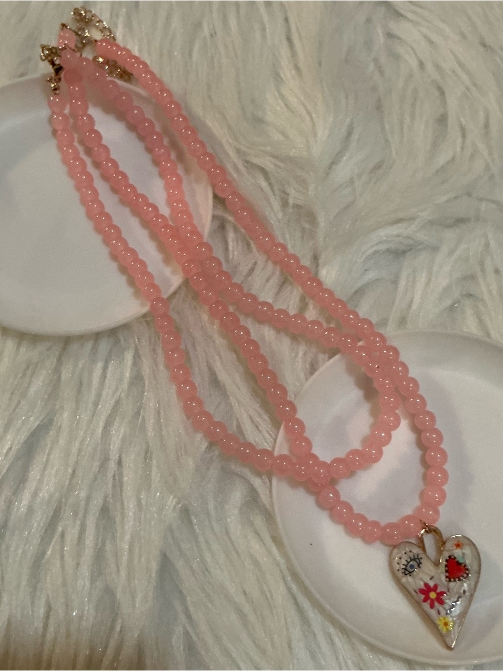 Two pink beaded necklaces, one with a heart pendant charm